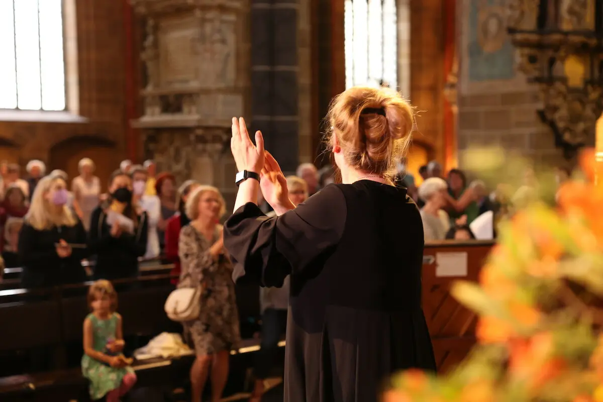 Frau dirigiert Gemeindegesang in der Kirche