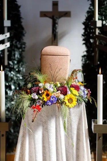 Urne steht vor einem geschmückten Altar bei einer Trauerfeier.