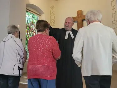 Pfarrer segnet Seniorinnen im Gottesdienst.